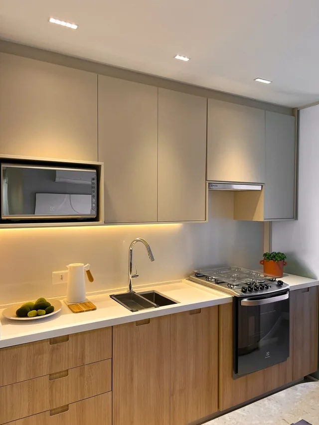 Cozinha em tons claros com armários planejados e iluminação na bancada