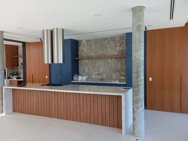 Cozinha integrada com ilha, armários amadeirados e acabamentos azuis