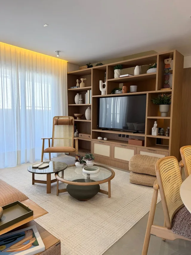 Sala de estar com estante de madeira, televisão e poltronas